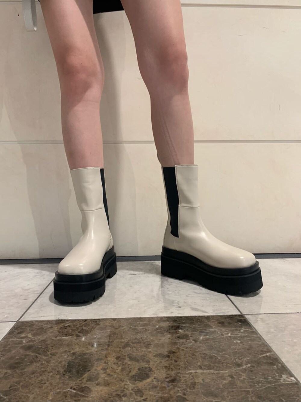 ブラック系のスカート、ホワイト系のハンドバッグ、グリーン系のニット/セーターを着用したレディースの夏コーディネートの4枚目の写真