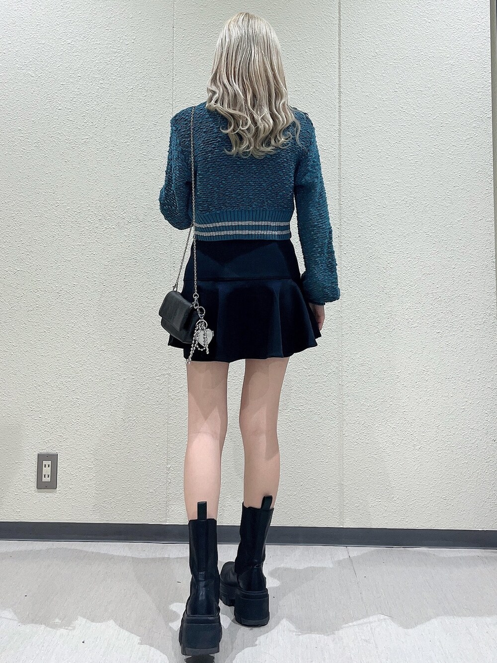 グリーン系のカーディガン/ボレロ、ブラック系のスカート、ブラック系のブーツを着用したレディースの冬コーディネートの3枚目の写真