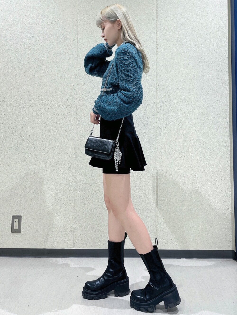 グリーン系のカーディガン/ボレロ、ブラック系のスカート、ブラック系のブーツを着用したレディースの冬コーディネートの2枚目の写真