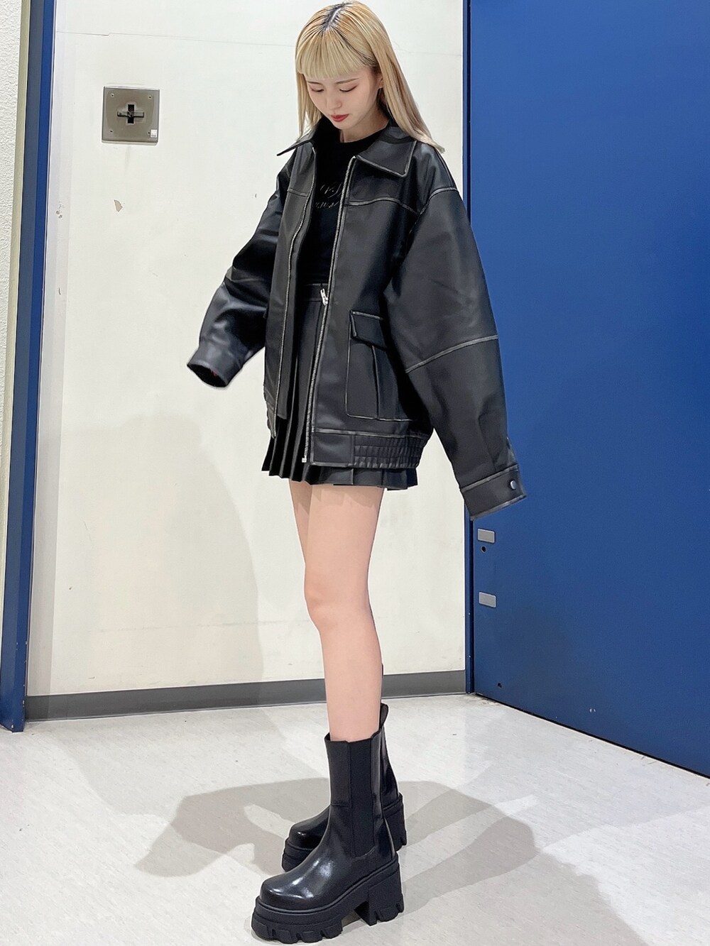 ブラック系のスカート、ブラック系のブルゾン、ブラック系のブーツを着用したレディースの夏コーディネートの2枚目の写真