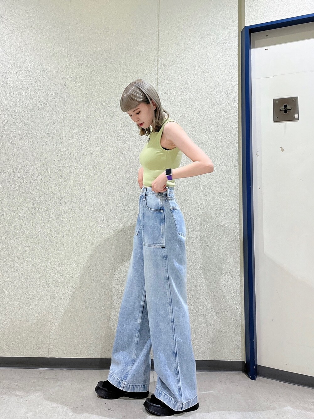 イエロー系のタンクトップ、ブルー系のデニムパンツ、ブラック系のサンダルを着用したレディースの夏コーディネートの2枚目の写真