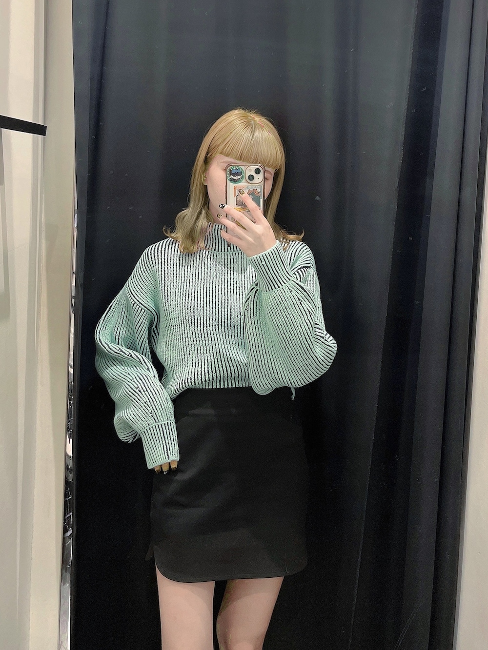 ブラック系のブルゾン、グリーン系のニット/セーター、ブラック系のスカートを着用したレディースの秋コーディネートの2枚目の写真