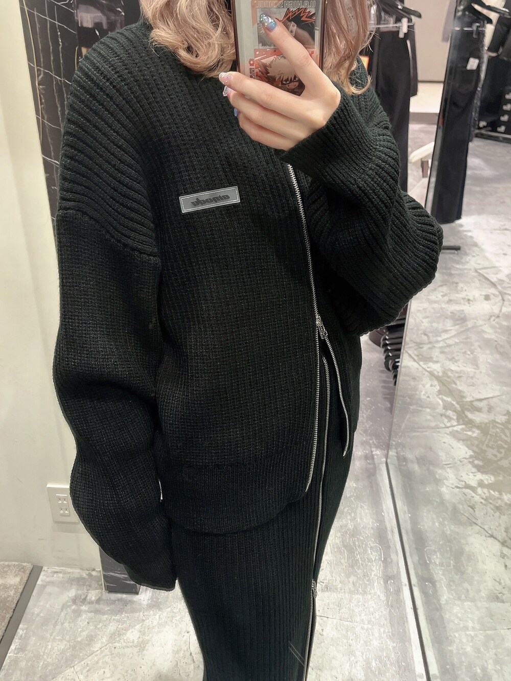 ブラック系のスカート、ブラック系のニット/セーター、ブラック系のブーツを着用したレディースの秋コーディネートの4枚目の写真