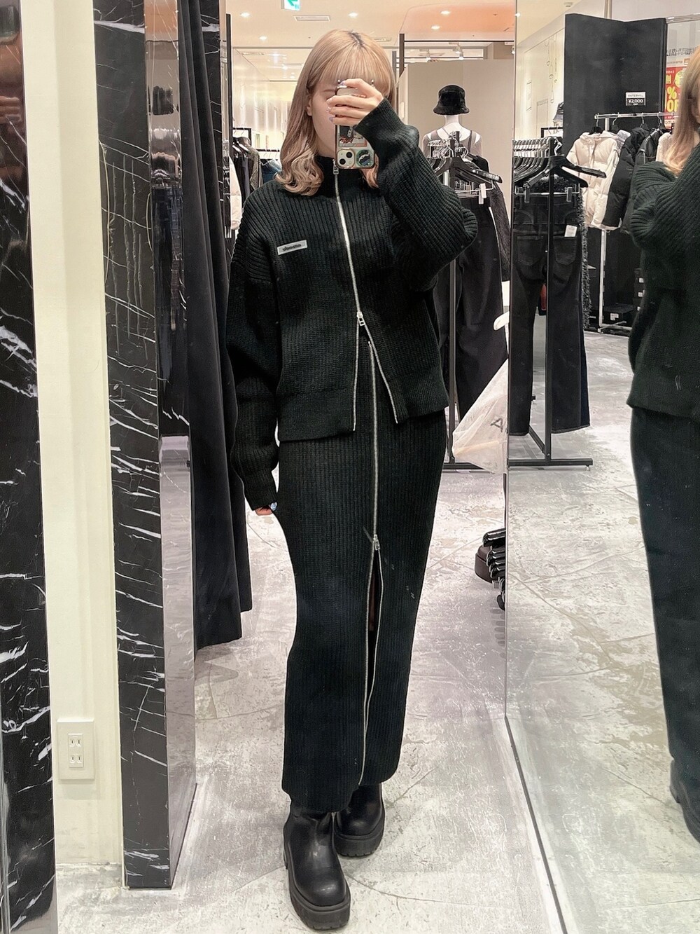 ブラック系のスカート、ブラック系のニット/セーター、ブラック系のブーツを着用したレディースの秋コーディネートの3枚目の写真