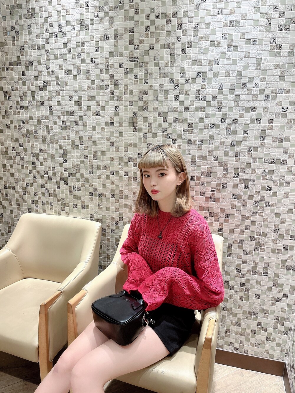 ピンク系のニット/セーター、ブラック系のハンドバッグ、ホワイト系のブーツを着用したレディースの冬コーディネートの3枚目の写真