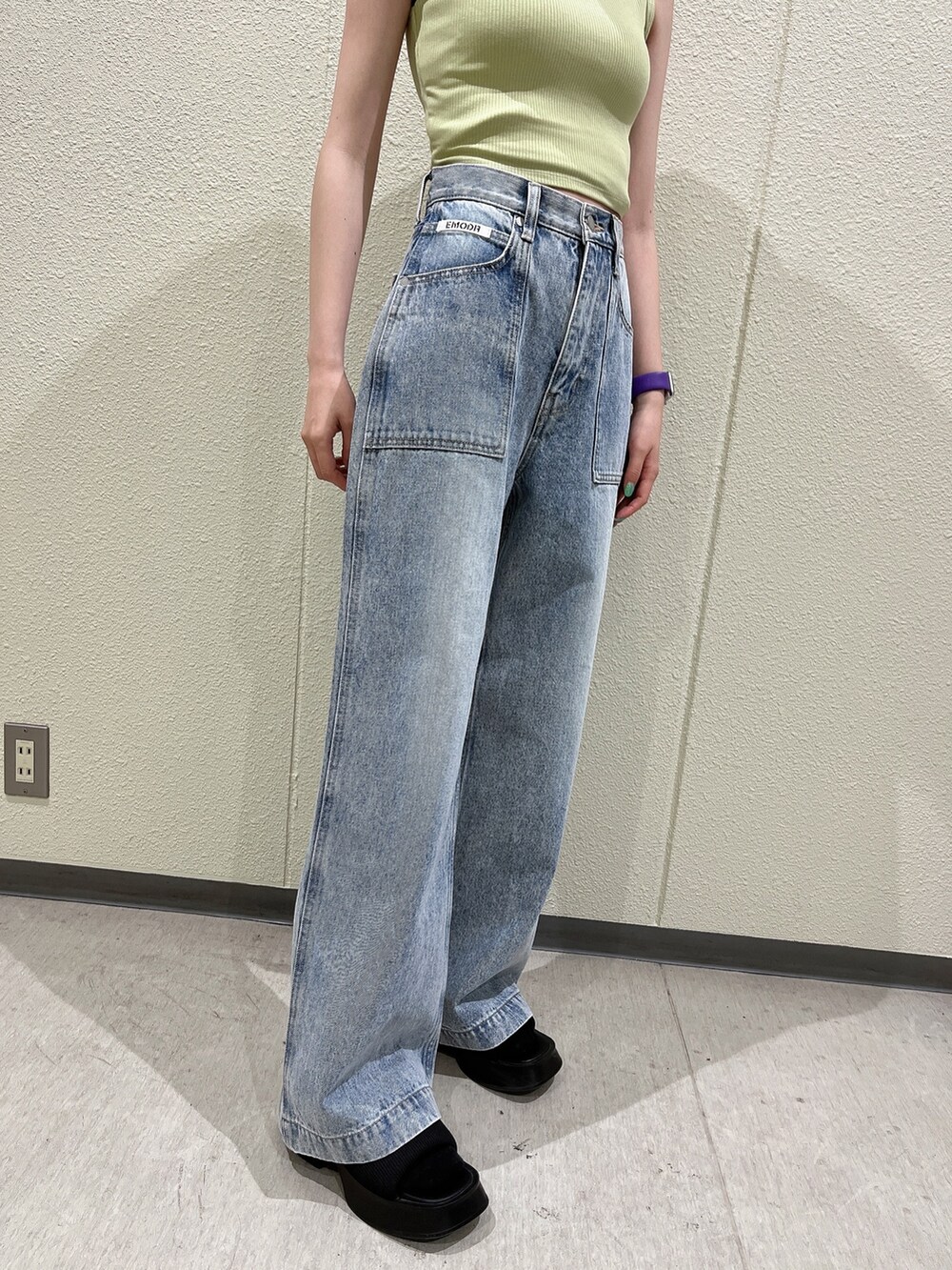 イエロー系のタンクトップ、ブルー系のデニムパンツ、ブラック系のサンダルを着用したレディースの夏コーディネートの3枚目の写真