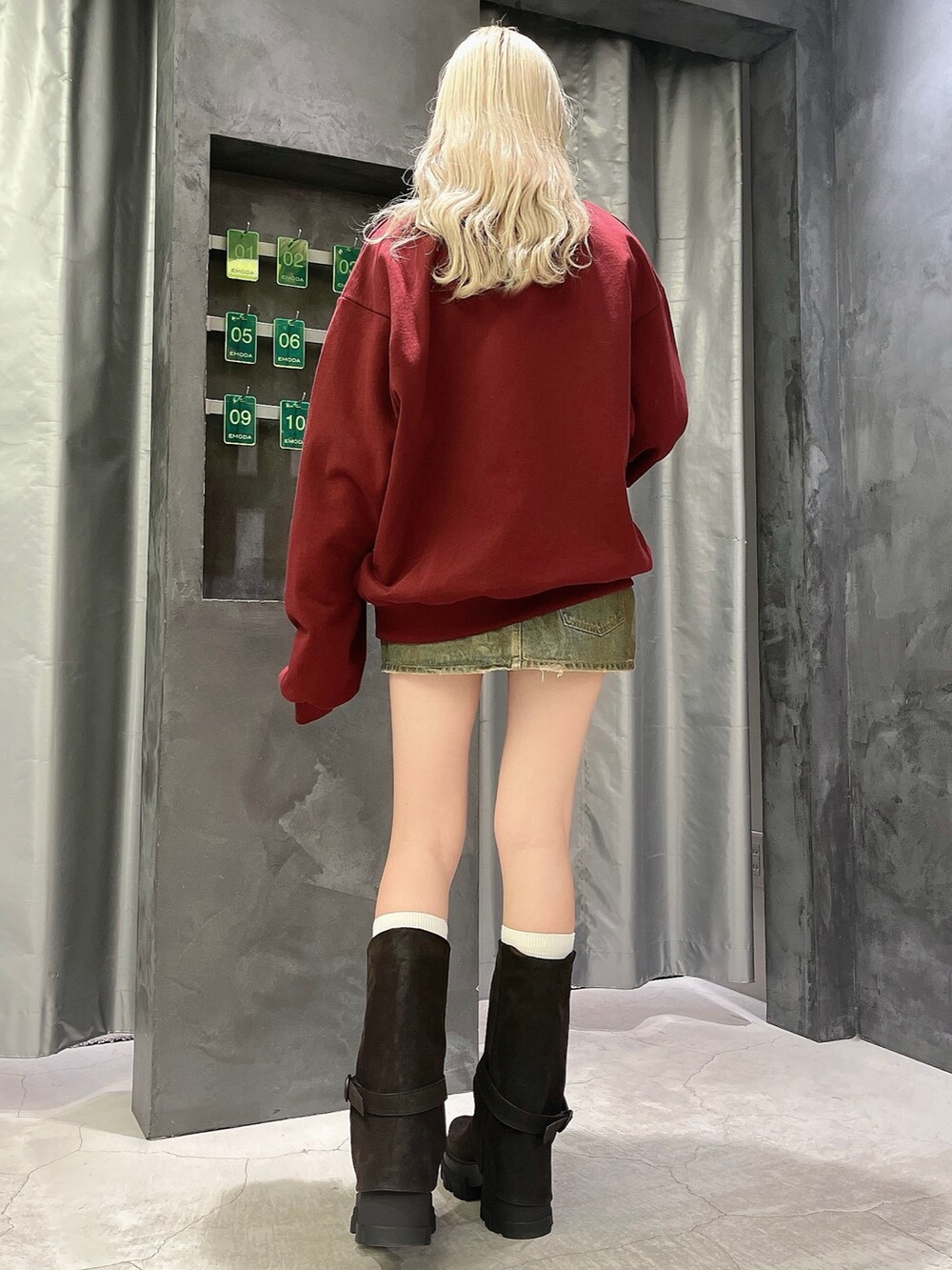 レッド系のスウェット、ブラウン系のスカート、ブラック系のブーツを着用したレディースの冬コーディネートの3枚目の写真