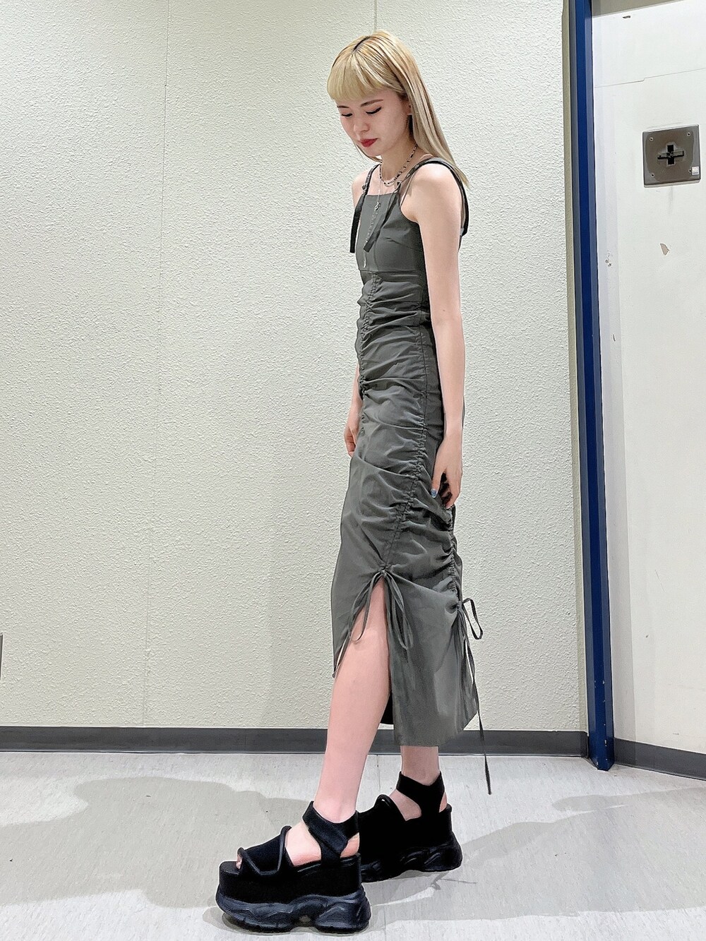 グリーン系のワンピース、ブラック系のサンダル、ブラック系のネックレスを着用したレディースの春コーディネートの3枚目の写真