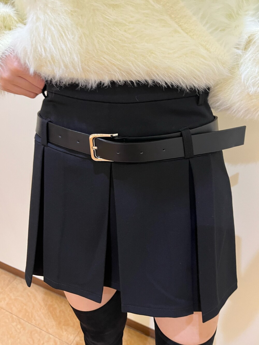 ブラック系のスカート、ホワイト系のニット/セーター、ブラック系のブーツを着用したレディースの秋コーディネートの3枚目の写真