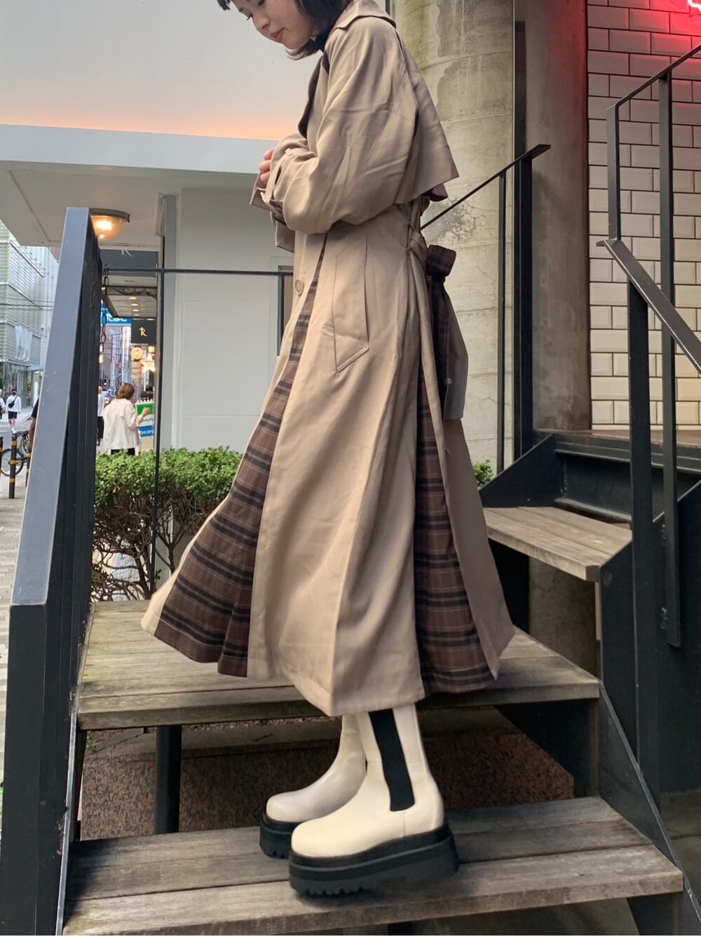 ベージュ系のトレンチコート、ブラック系のワンピースを着用したレディースの夏コーディネートの3枚目の写真