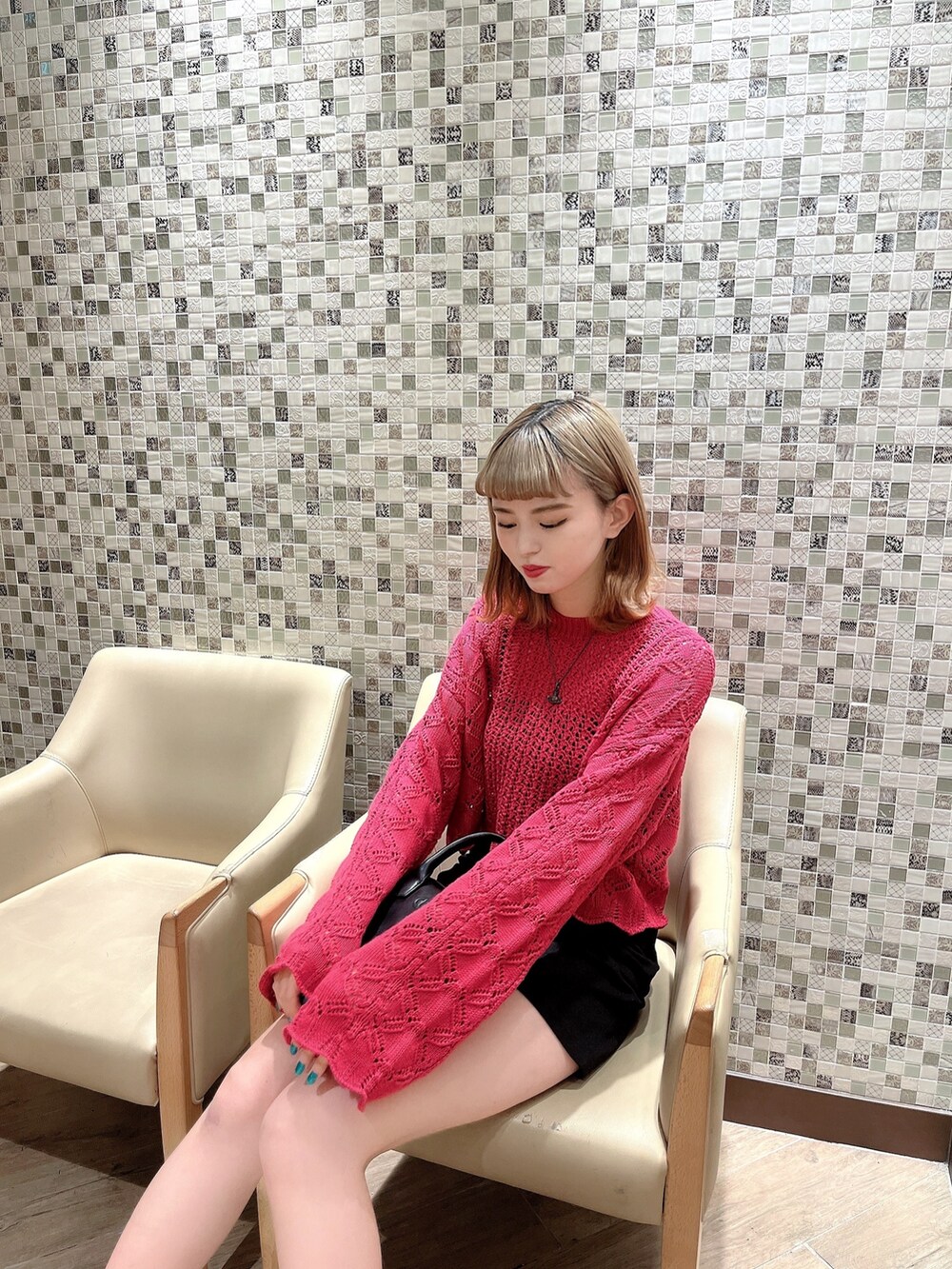 ピンク系のニット/セーター、ブラック系のハンドバッグ、ホワイト系のブーツを着用したレディースの冬コーディネートの2枚目の写真