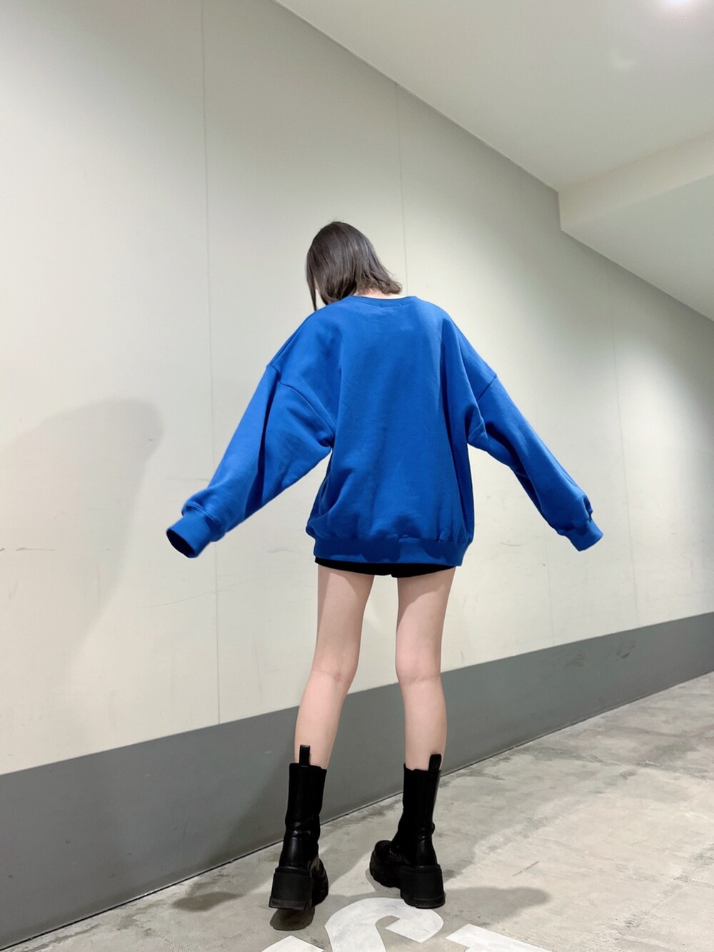 ブルー系のスウェット、ブラック系のスカート、ブラック系のブーツを着用したレディースの冬コーディネートの3枚目の写真