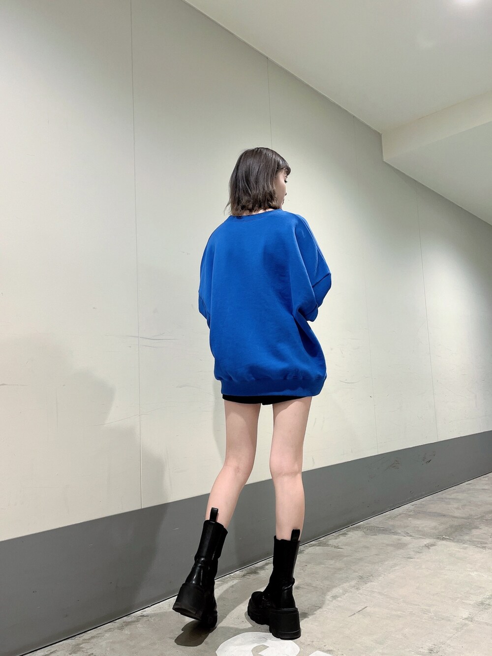 ブルー系のスウェット、ブラック系のスカート、ブラック系のブーツを着用したレディースの冬コーディネートの2枚目の写真