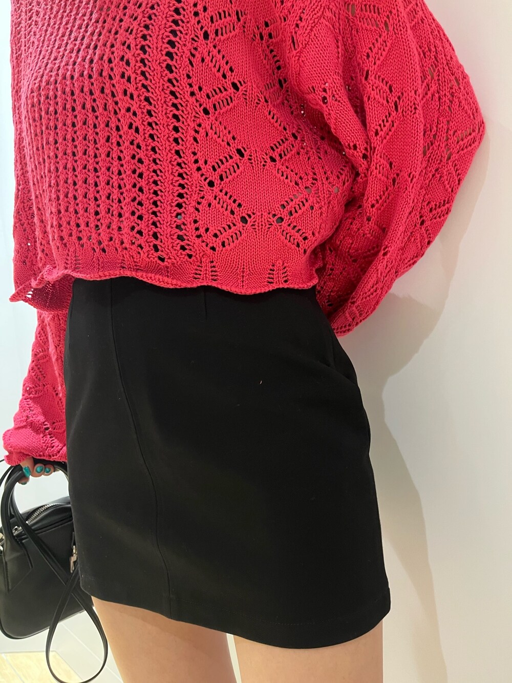 ピンク系のニット/セーター、ブラック系のハンドバッグ、ホワイト系のブーツを着用したレディースの冬コーディネートの5枚目の写真