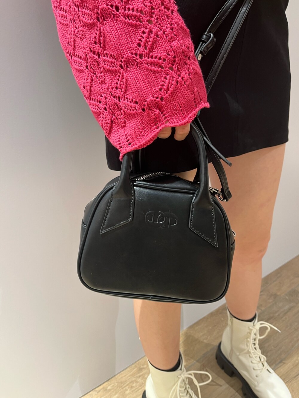 ピンク系のニット/セーター、ブラック系のハンドバッグ、ホワイト系のブーツを着用したレディースの冬コーディネートの6枚目の写真