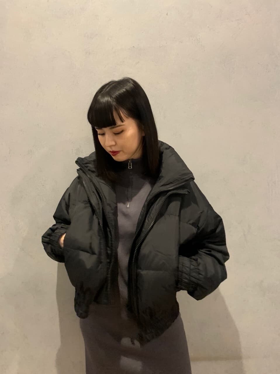 グレー系のワンピース、ブラック系のダウンジャケット/コート、ブラック系のブーツを着用したレディースの冬コーディネートの3枚目の写真