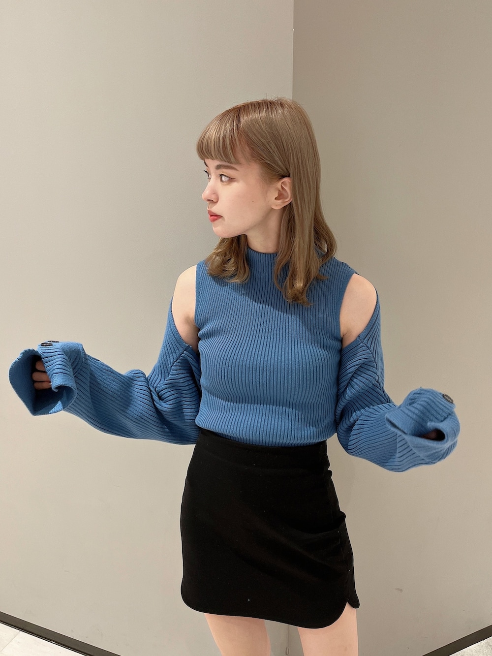 ブルー系のニット/セーター、ブラック系のスカート、ブラック系のブーツを着用したレディースの秋コーディネートの2枚目の写真