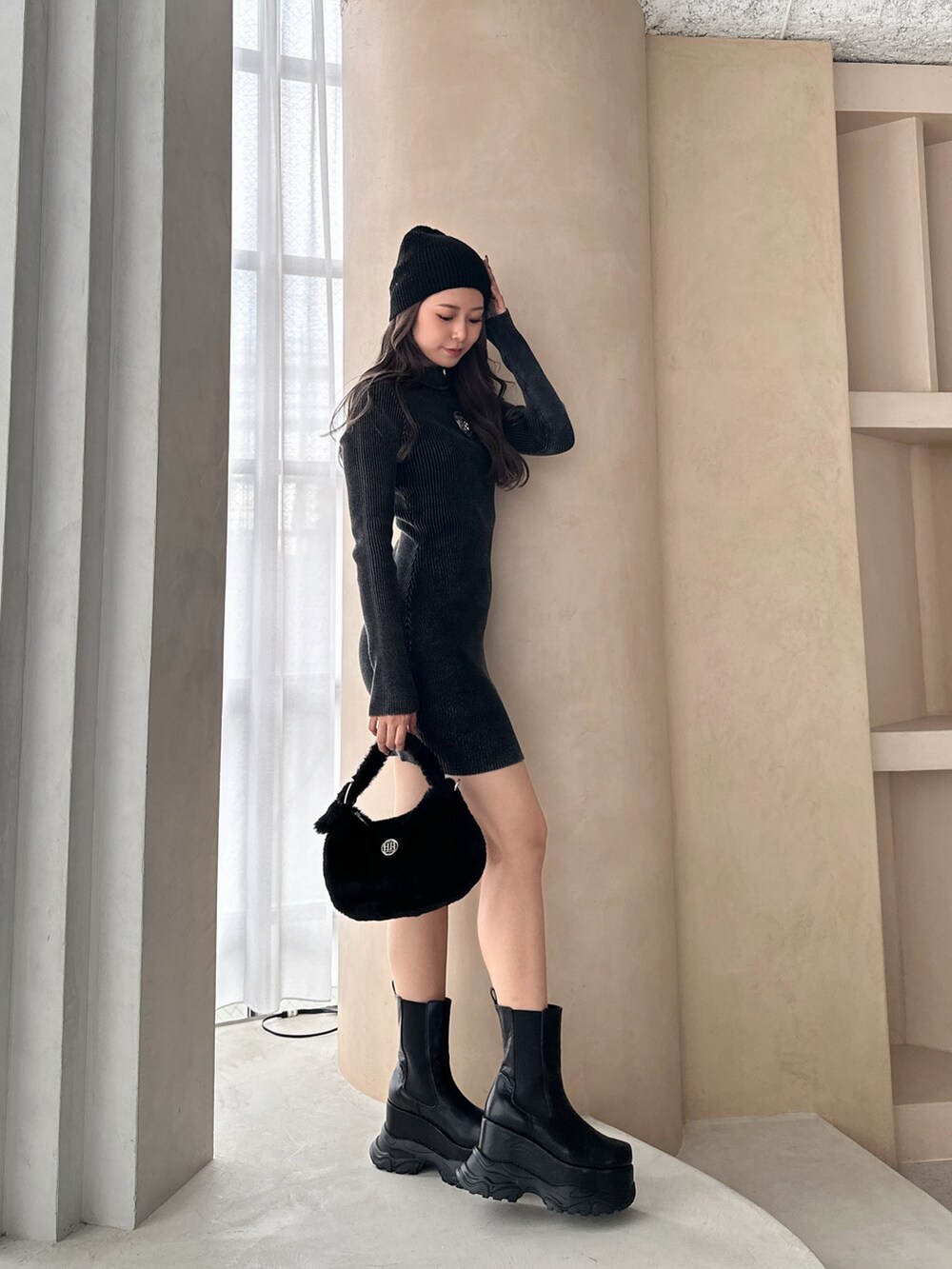 ブラック系のワンピース、ブラック系のブーツ、ブラック系のニットキャップ/ビーニーを着用したレディースの冬コーディネートの3枚目の写真