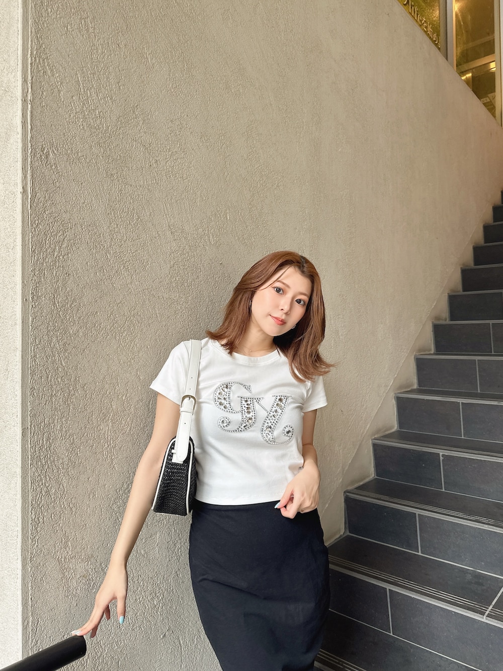 ブラック系のハンドバッグ、ホワイト系のTシャツ/カットソーを着用したレディースの夏コーディネートの3枚目の写真