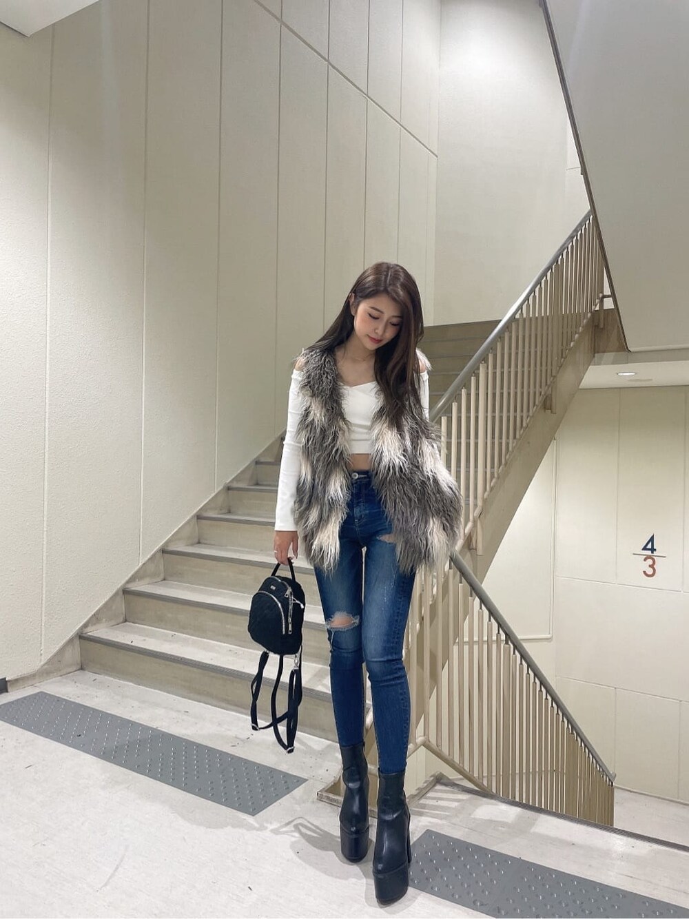 ブラック系のブーツ、ブルー系のデニムパンツ、ブラック系のバックパック/リュックを着用したレディースの秋コーディネートの2枚目の写真