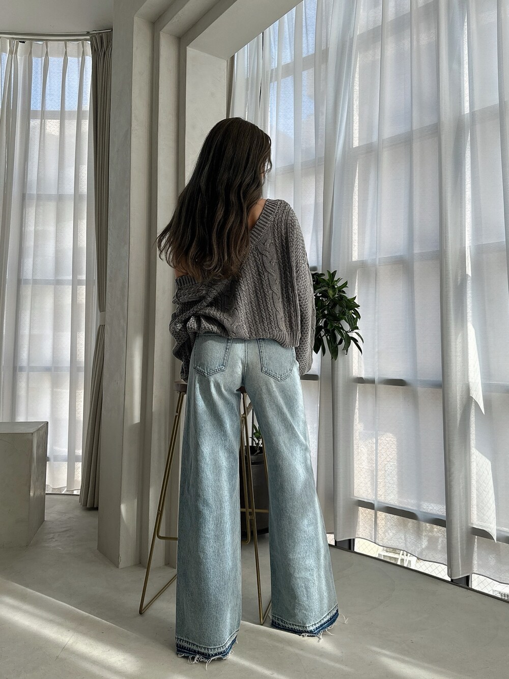 ブルー系のニット/セーター、ブルー系のデニムパンツ、ホワイト系のパンプスを着用したレディースの夏コーディネートの4枚目の写真