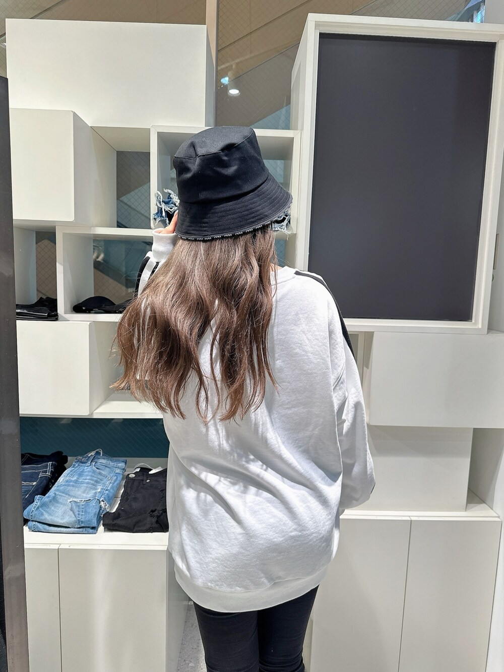 ホワイト系のスウェット、ブラック系のデニムパンツを着用したレディースの冬コーディネートの5枚目の写真