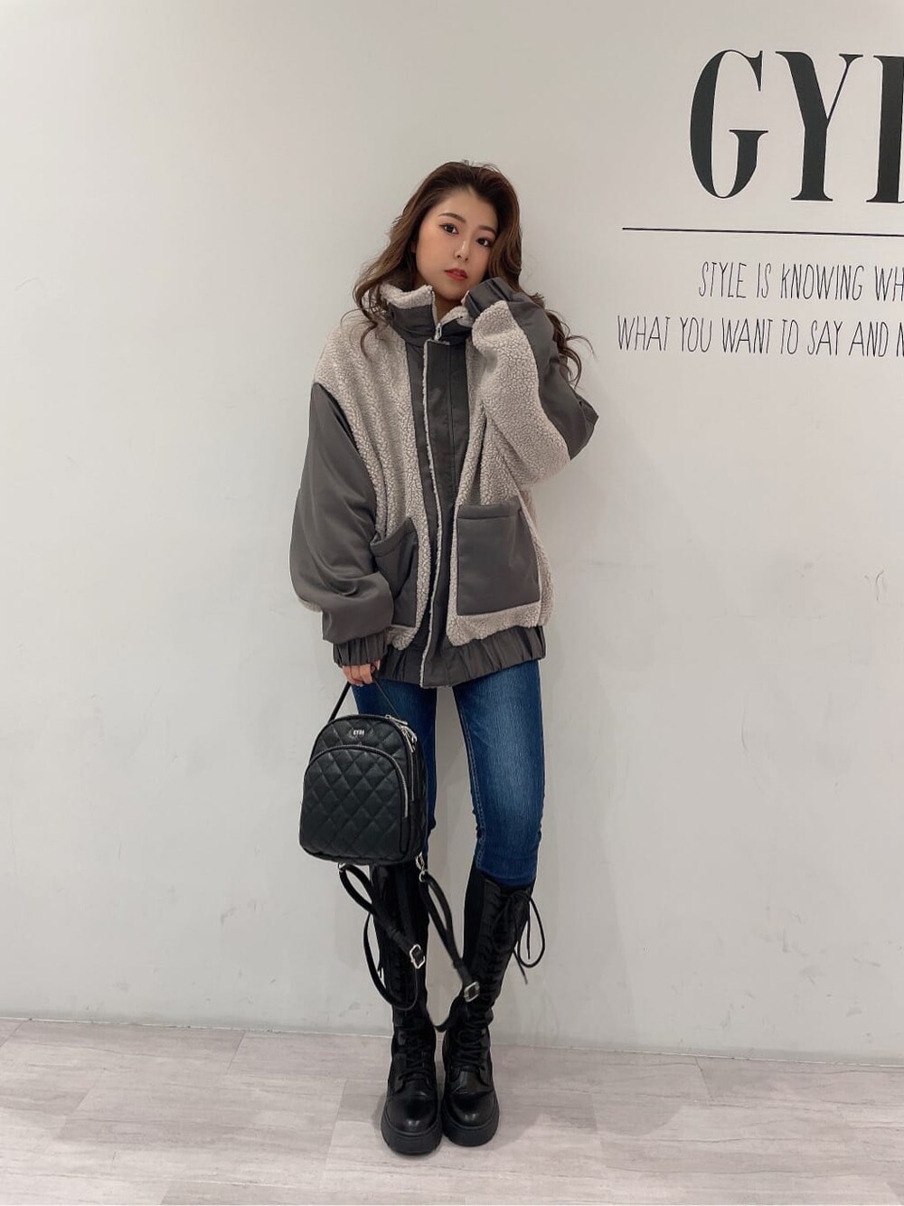 ブラック系のバックパック/リュック、ブラック系のブーツ、ブルー系のデニムパンツを着用したレディースの秋コーディネートの2枚目の写真