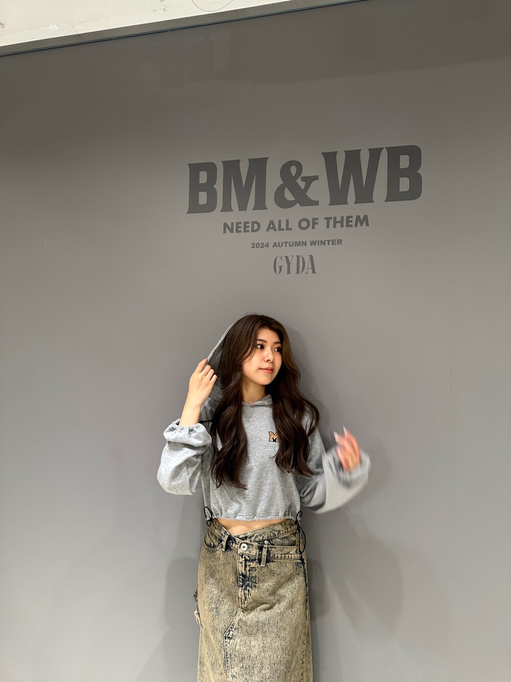 グレー系のパーカー、ブルー系のデニムスカート、ブラック系のブルゾンを着用したレディースの秋コーディネートの7枚目の写真