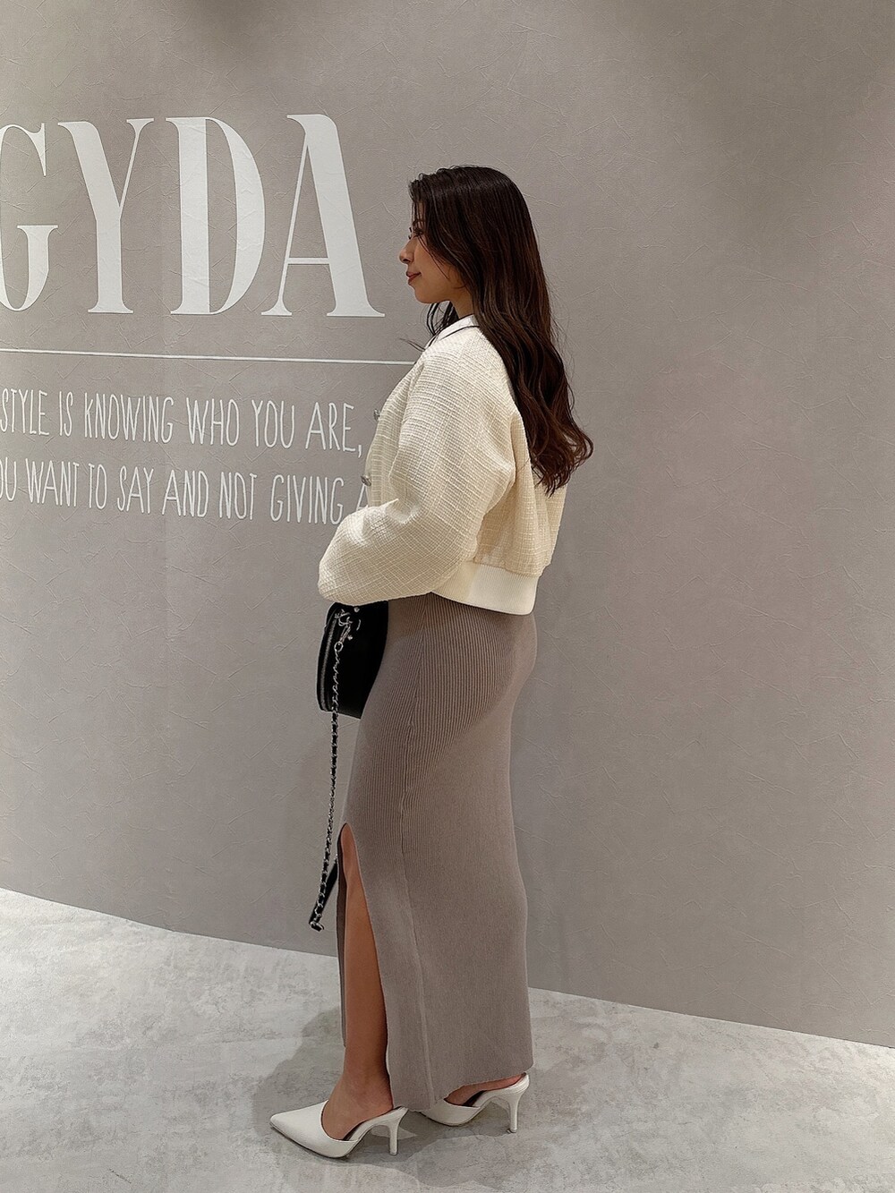 グレー系のワンピース、ホワイト系のブルゾン、ブラック系のハンドバッグを着用したレディースの春コーディネートの4枚目の写真