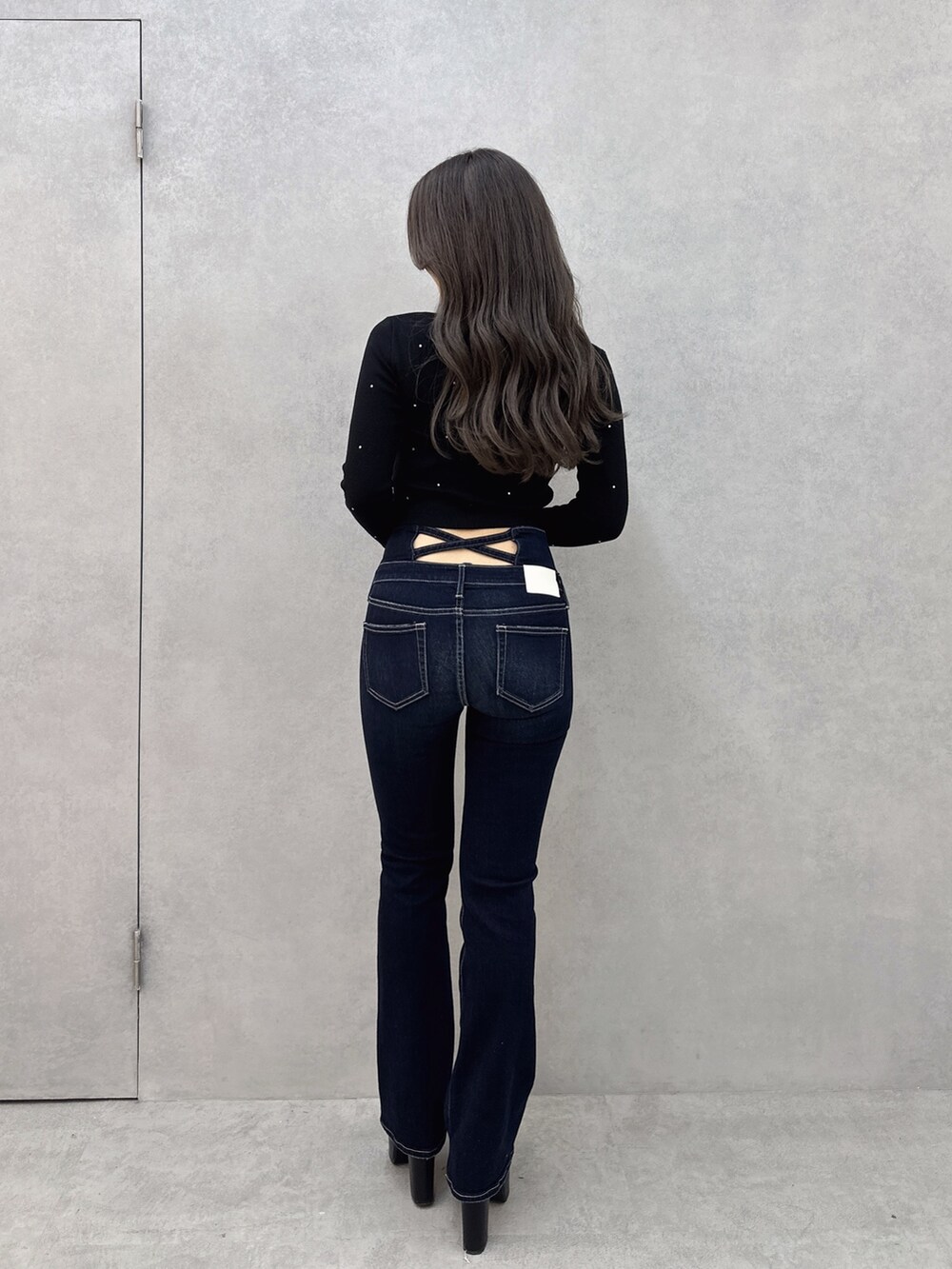 ブルー系のデニムパンツ、ブラック系のブーツ、ブラック系のニット/セーターを着用したレディースの冬コーディネートの2枚目の写真