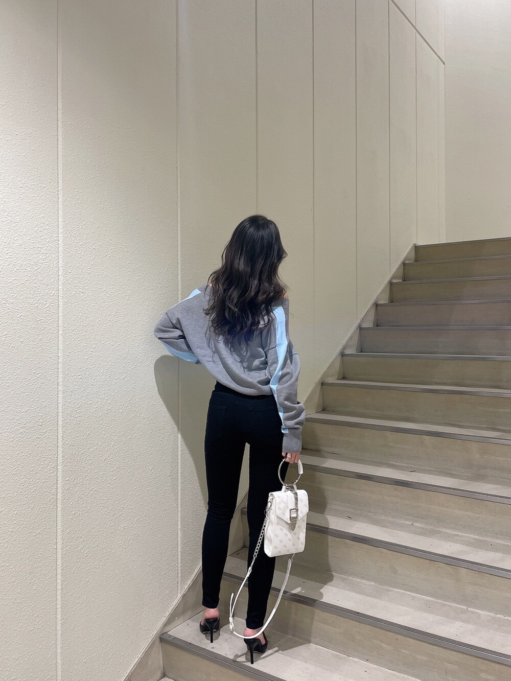 グレー系のニット/セーター、ブラック系のデニムパンツ、ホワイト系のパンプスを着用したレディースの冬コーディネートの2枚目の写真