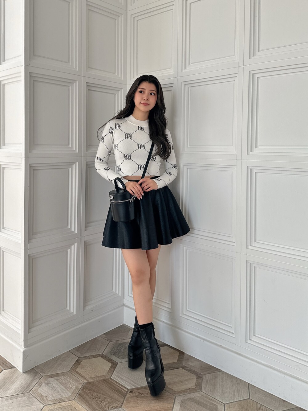 ブラック系のスカート、ブラック系のハンドバッグ、ホワイト系のニット/セーターを着用したレディースの冬コーディネートの2枚目の写真