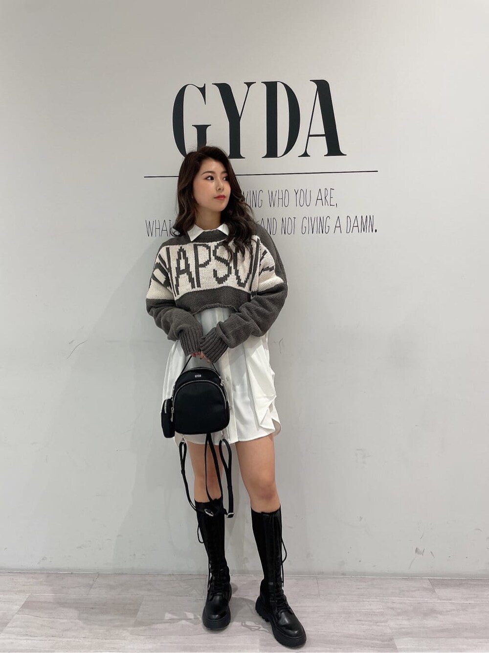 ブラック系のその他シューズ、ブラック系のバックパック/リュック、ホワイト系のシャツ/ブラウスを着用したレディースの冬コーディネートの2枚目の写真