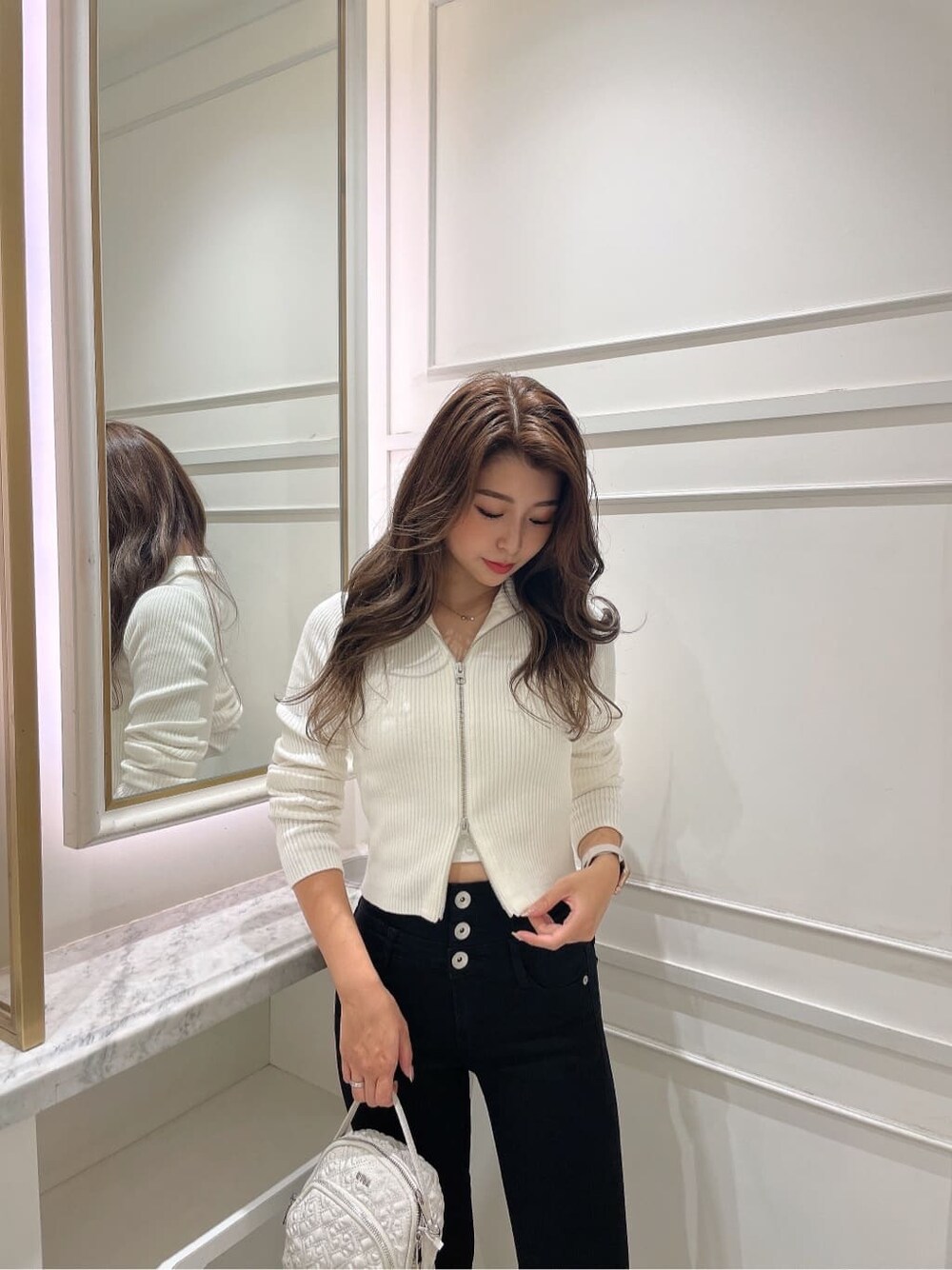 ホワイト系のバックパック/リュック、ホワイト系のニット/セーター、ブラック系のブーツを着用したレディースの秋コーディネートの2枚目の写真