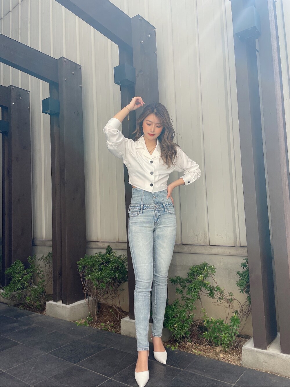 ブルー系のデニムパンツ、ブラック系のチューブトップ、ホワイト系のパンプスを着用したレディースの春コーディネートの5枚目の写真