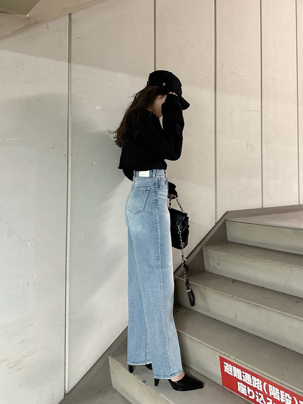 ブラック系のスウェット、ブルー系のデニムパンツ、ブラック系のバックパック/リュックを着用したレディースの冬コーディネートの5枚目の写真