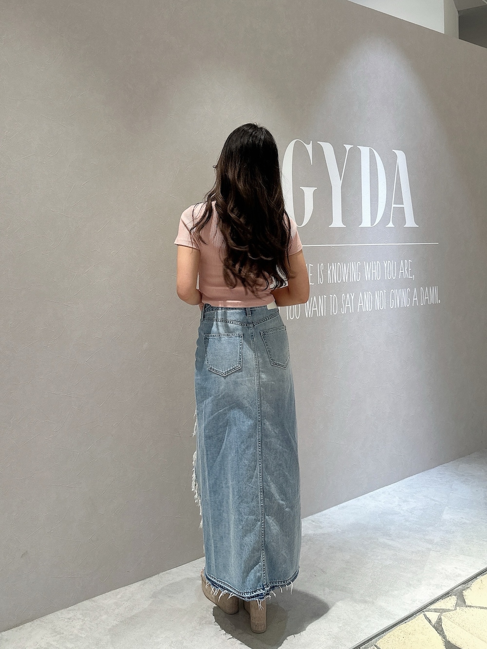 ブルー系のデニムスカート、ホワイト系のサンダル、ピンク系のTシャツ/カットソーを着用したレディースの春コーディネートの3枚目の写真