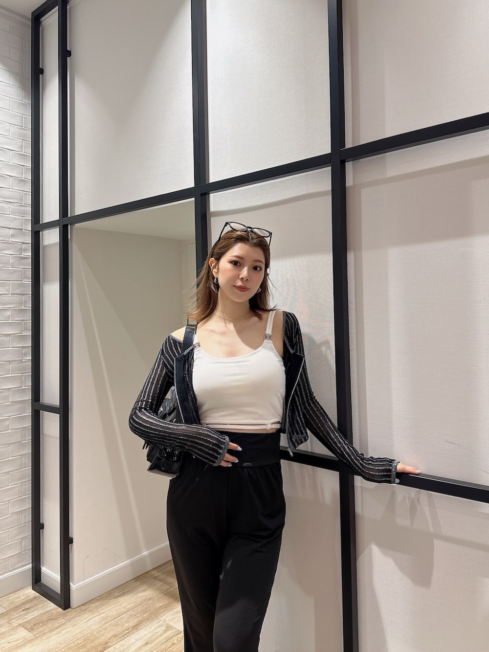 ブラック系のハンドバッグ、ブラック系のカーディガン/ボレロ、ホワイト系のキャミソールを着用したレディースの夏コーディネートの4枚目の写真