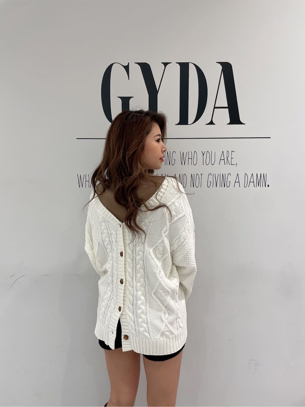 ブラック系のデニムパンツ、ブラウン系のブーツ、ベージュ系のニット/セーターを着用したレディースの秋コーディネートの3枚目の写真