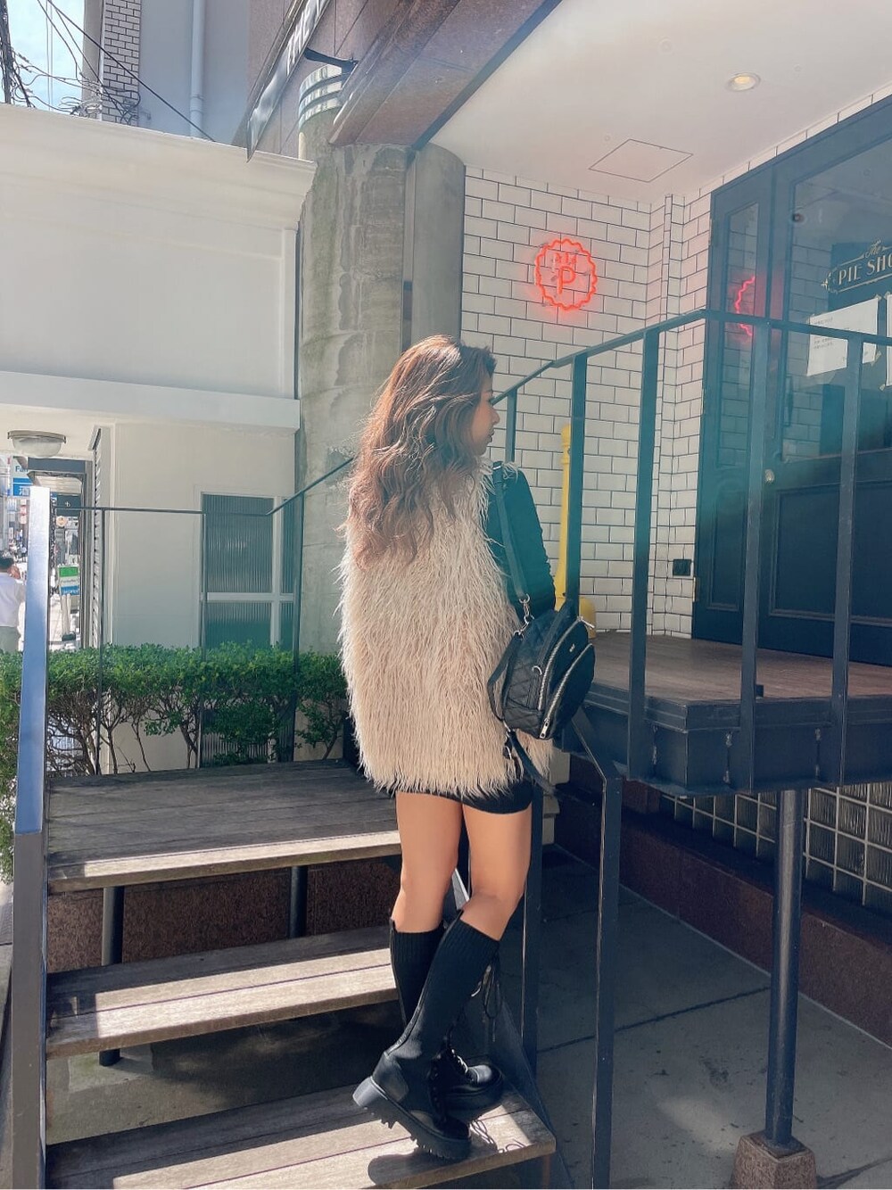 ブラック系のバックパック/リュック、ベージュ系のベスト、ブラック系のブーツを着用したレディースの秋コーディネートの4枚目の写真