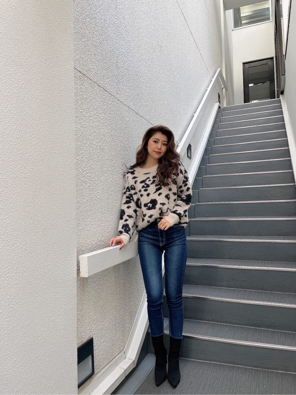 ホワイト系のニット/セーター、ブルー系のデニムパンツ、ブラック系のブーツを着用したレディースの秋コーディネートの2枚目の写真