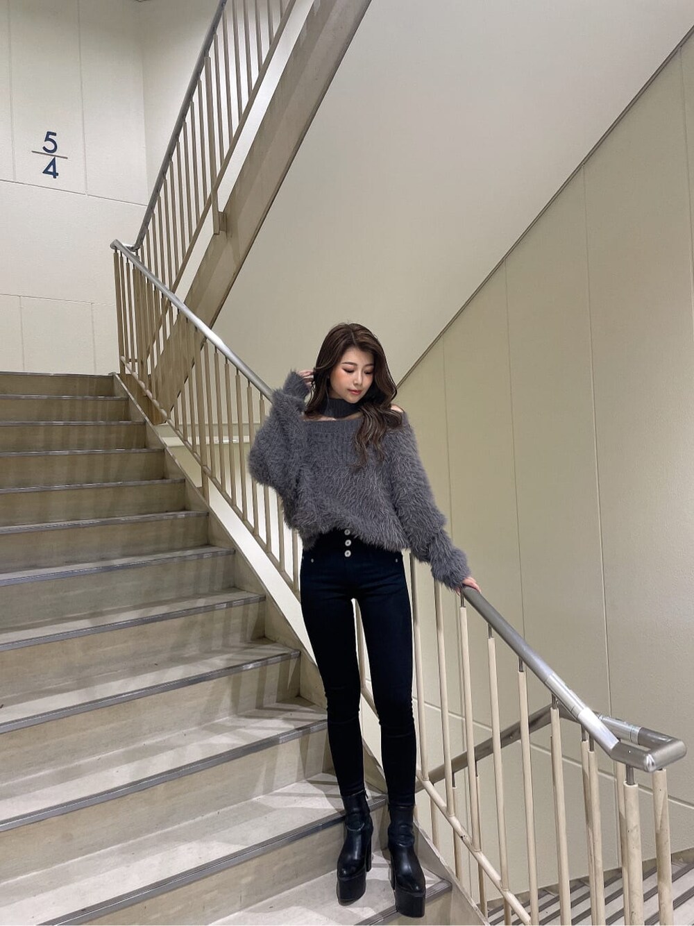 グレー系のニット/セーター、ブラック系のブーツ、ブラック系のチューブトップを着用したレディースの秋コーディネートの2枚目の写真