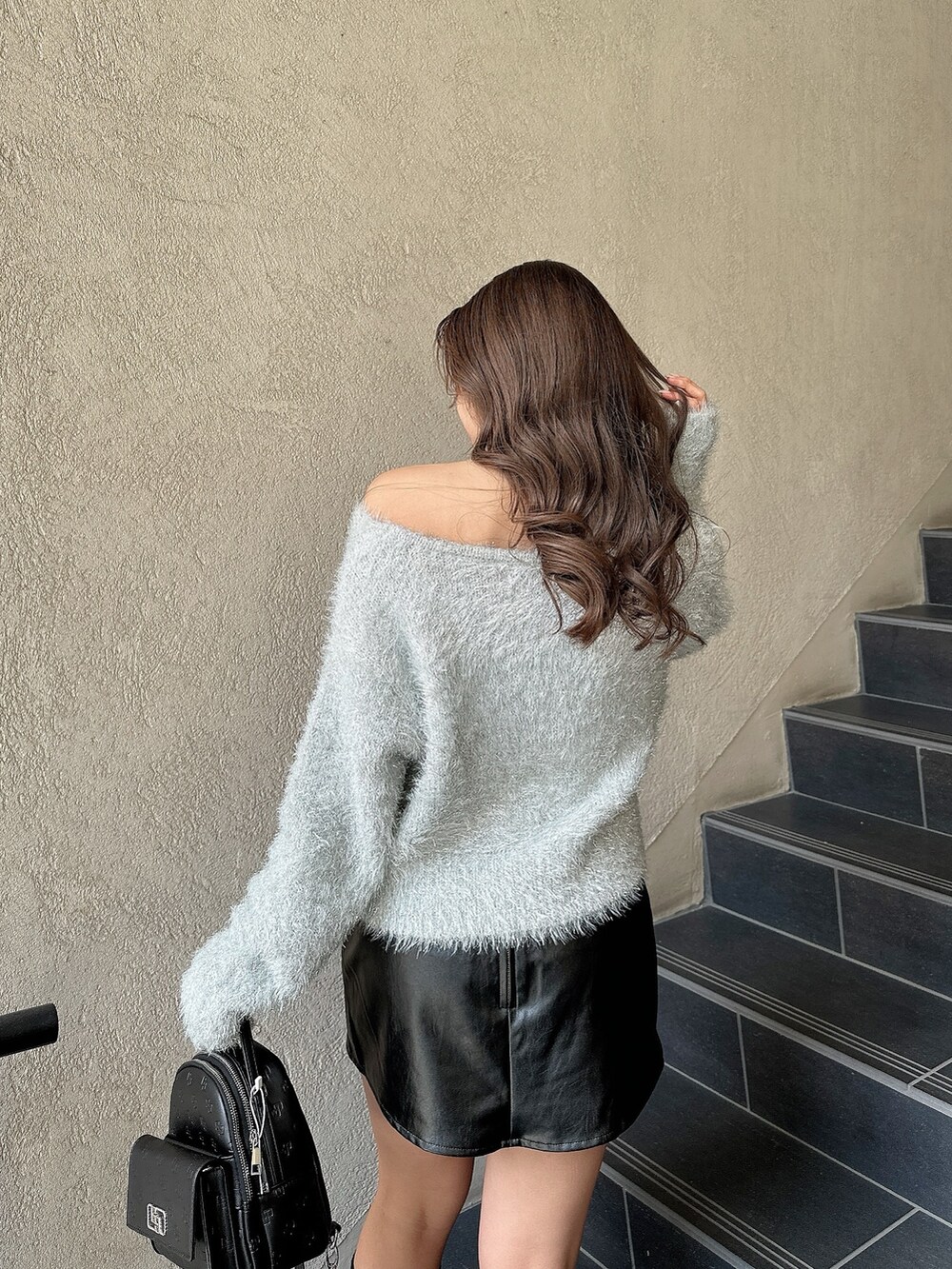 グレー系のニット/セーター、ブラック系のバックパック/リュック、ブラック系のブーツを着用したレディースの冬コーディネートの7枚目の写真
