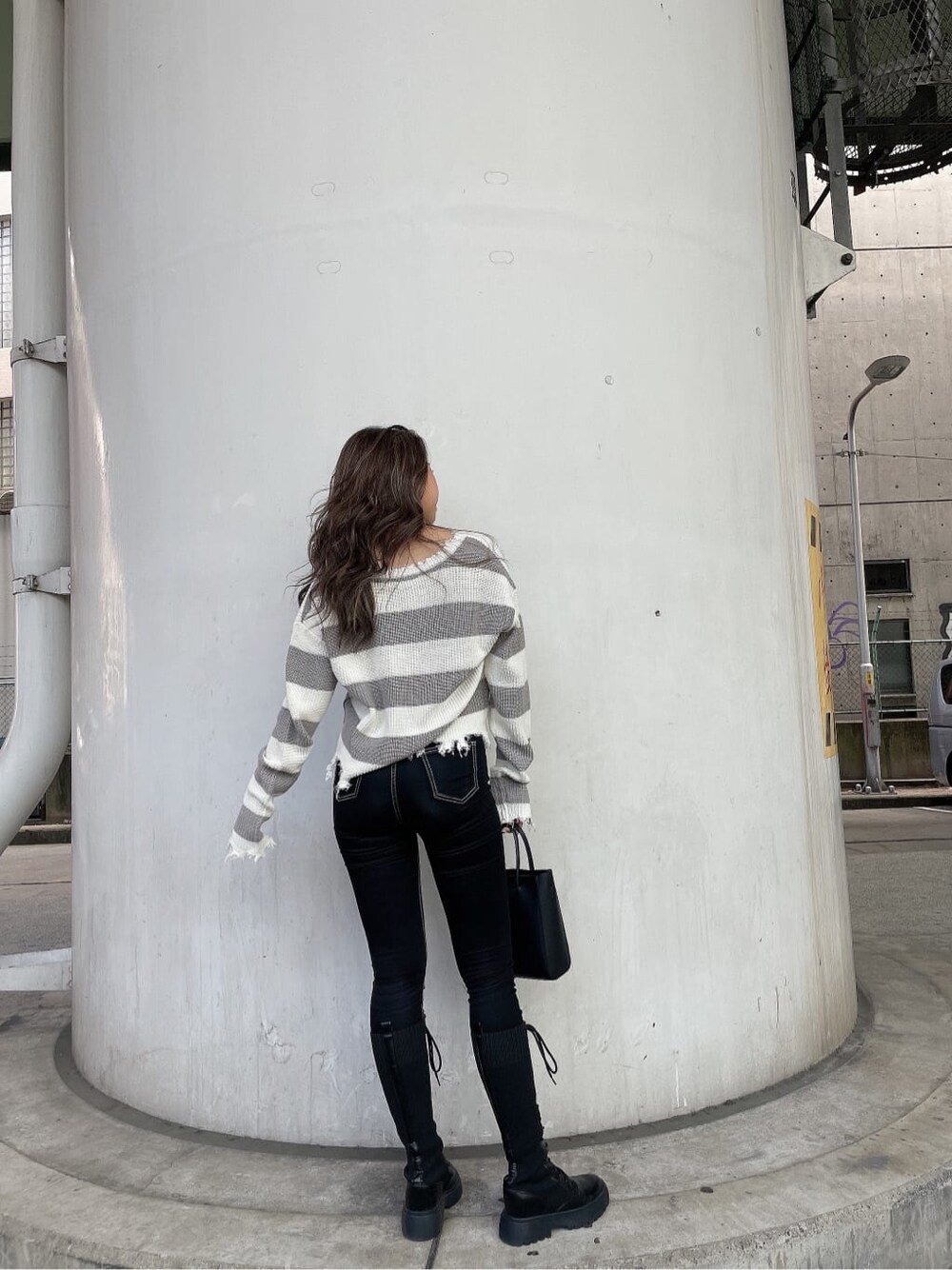 ブラック系のショルダーバッグ、ブラック系のデニムパンツ、グレー系のニット/セーターを着用したレディースの秋コーディネートの4枚目の写真