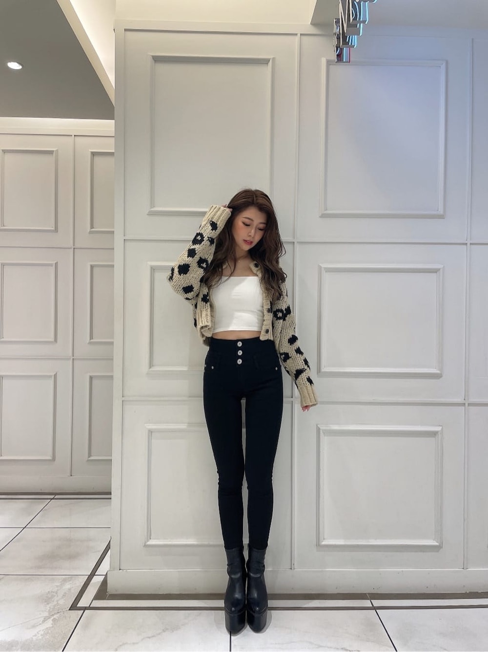ブラック系のブーツ、ホワイト系のキャミソール、ベージュ系のカーディガン/ボレロを着用したレディースの秋コーディネートの2枚目の写真