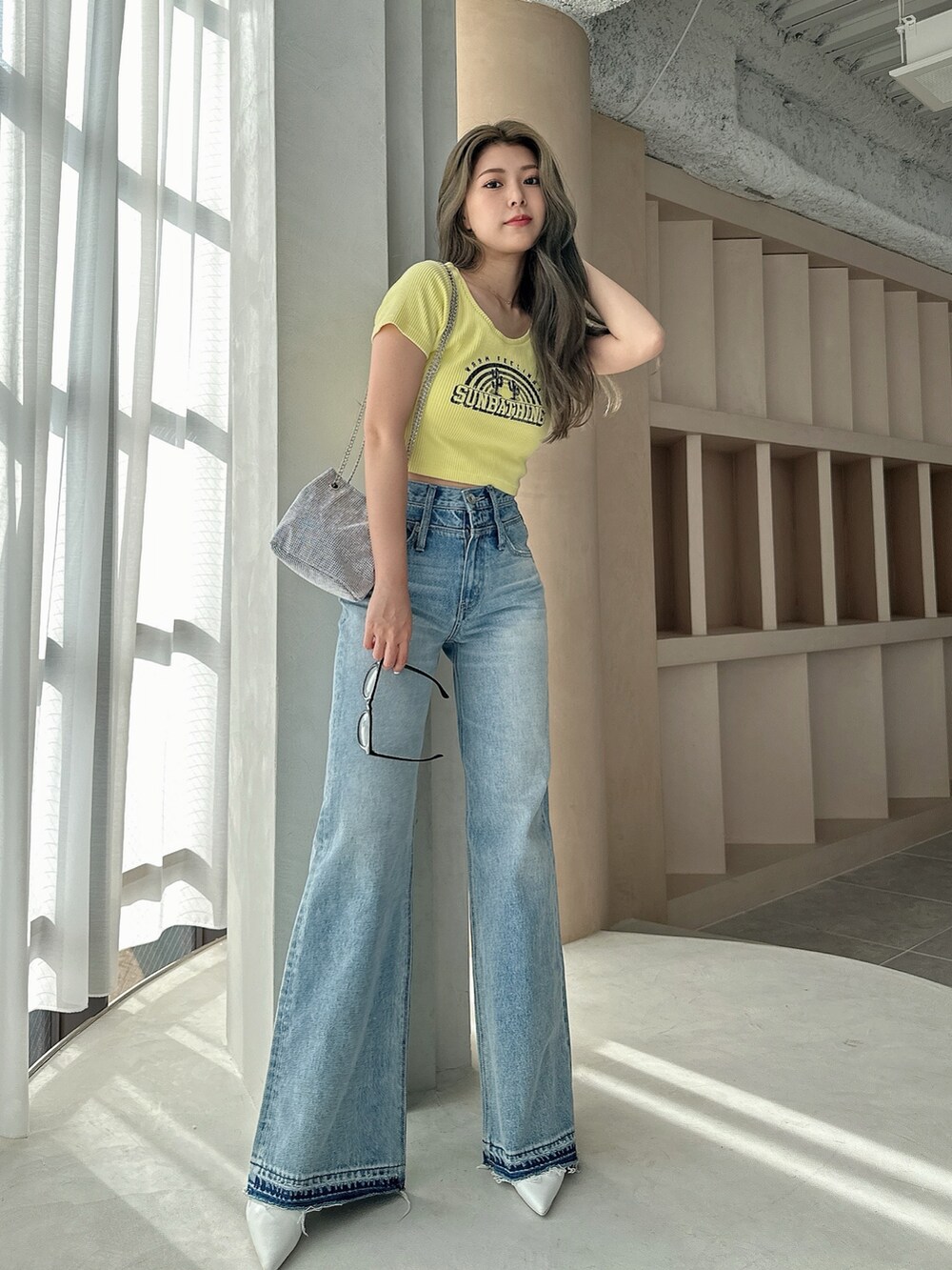 イエロー系のTシャツ/カットソー、シルバー系のショルダーバッグ、ブルー系のデニムパンツを着用したレディースの夏コーディネートの2枚目の写真