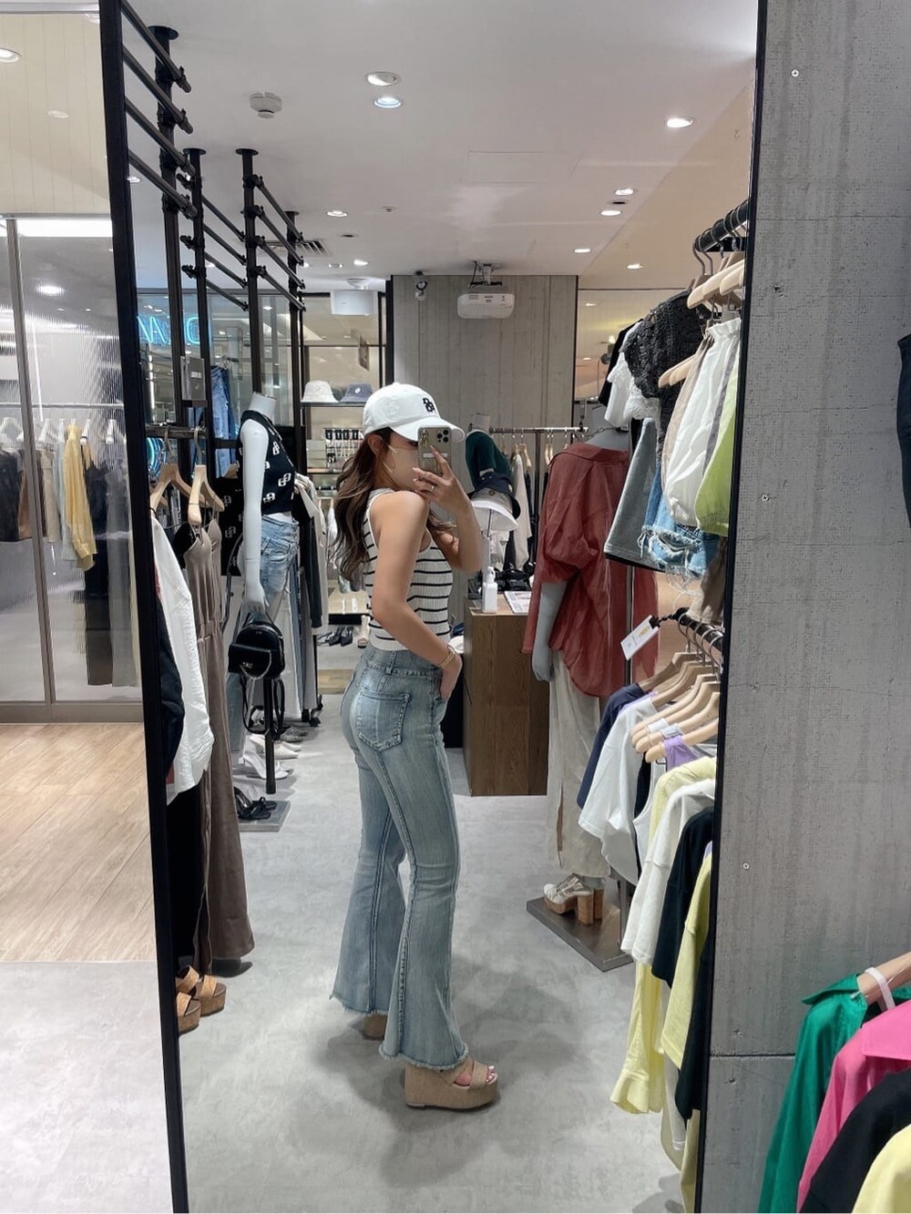 ホワイト系のサンダル、ホワイト系のタンクトップ、ブルー系のデニムパンツを着用したレディースの夏コーディネートの2枚目の写真