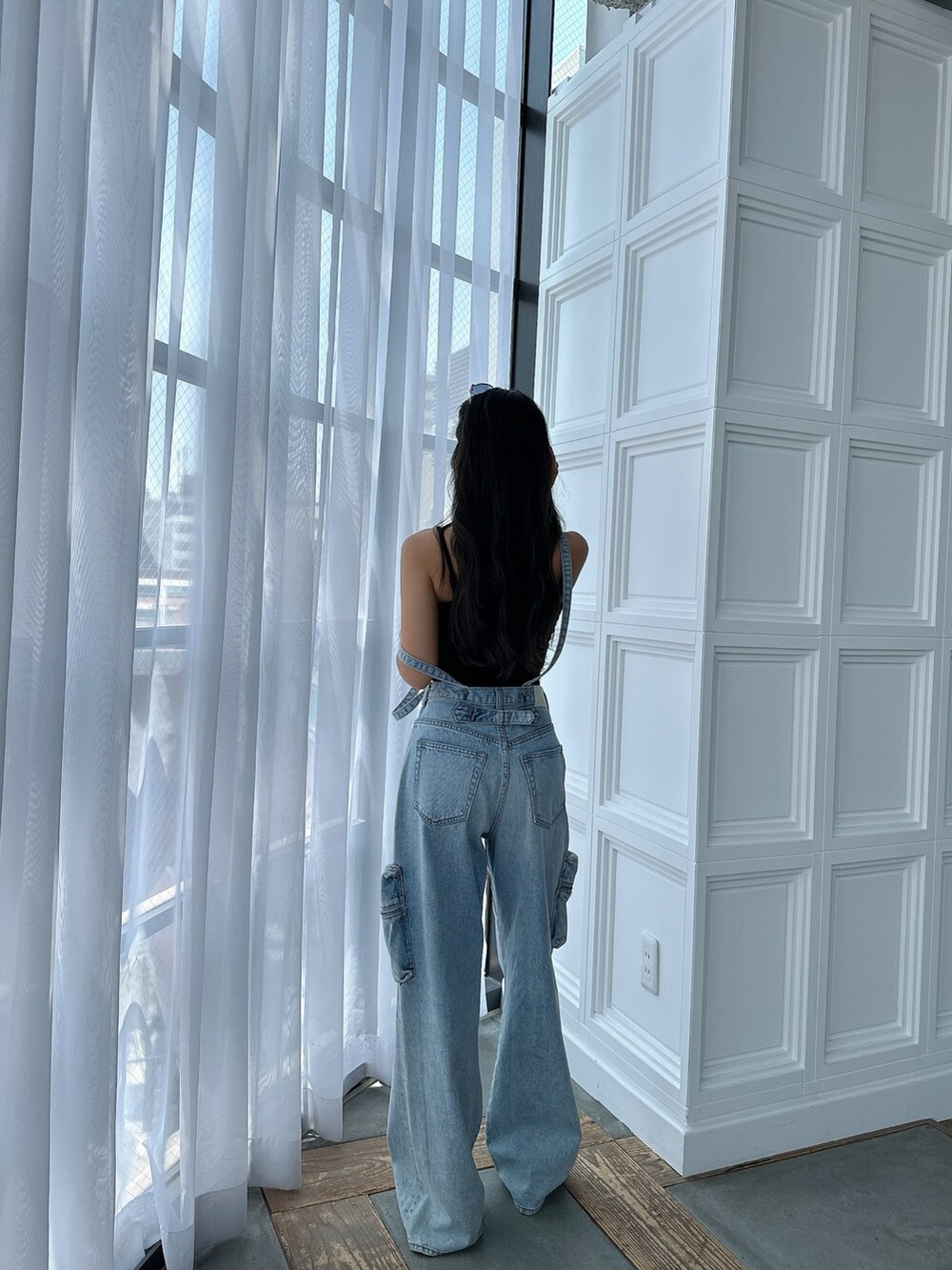 ブラック系のキャミソール、ブルー系のデニムパンツ、ブラック系のサンダルを着用したレディースの夏コーディネートの3枚目の写真