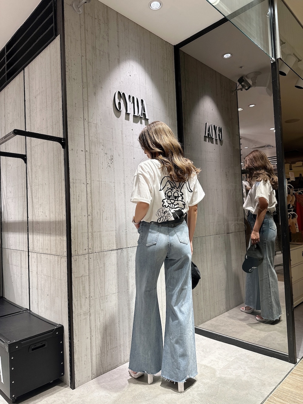 ブルー系のデニムパンツ、ホワイト系のサンダルを着用したレディースの夏コーディネートの2枚目の写真