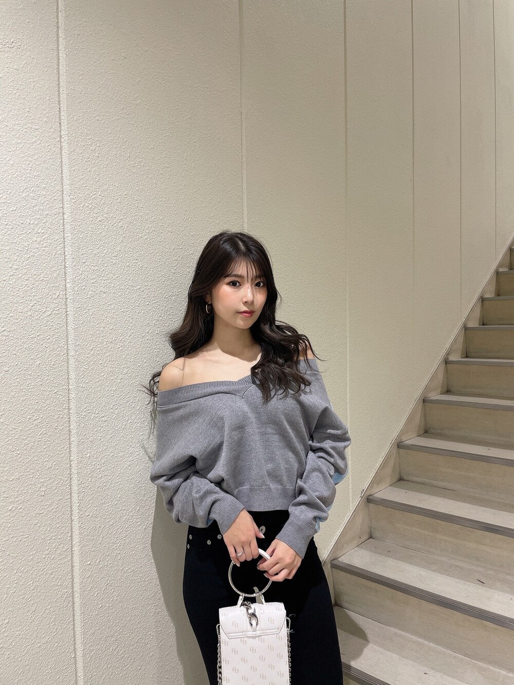 グレー系のニット/セーター、ブラック系のデニムパンツ、ホワイト系のパンプスを着用したレディースの冬コーディネートの4枚目の写真